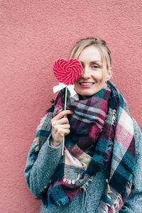 Portrait of a smiling young woman holding red wall