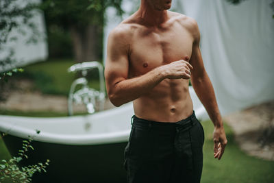 Full length of shirtless man standing outdoors