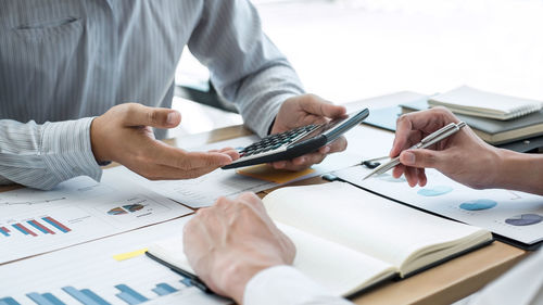 Midsection of man holding smart phone on table