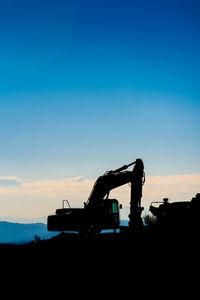 Silhouette construction site on field against sky during sunset
