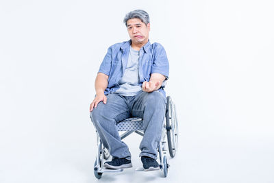 Portrait of man sitting on chair against white background