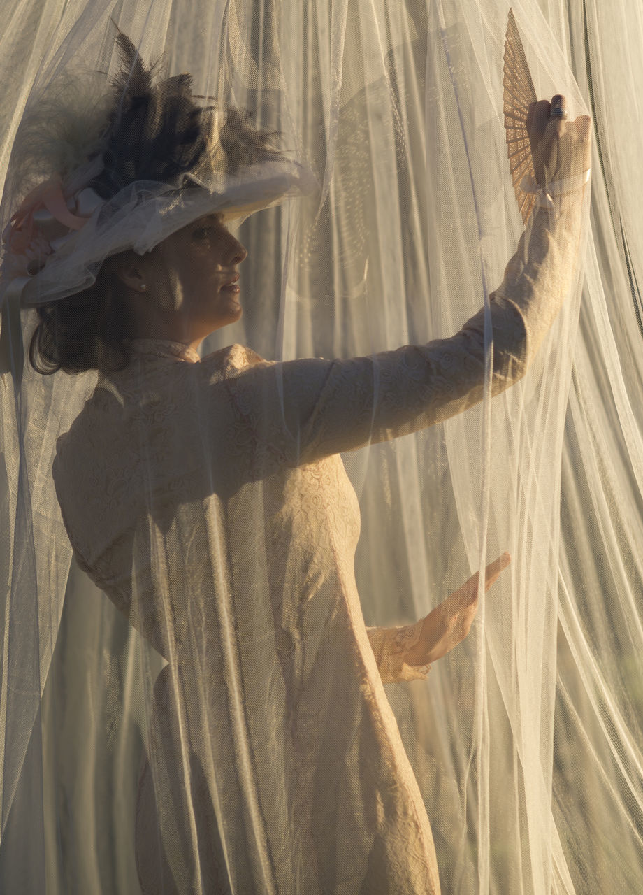 real people, curtain, one person, adult, young adult, women, young women, lifestyles, side view, textile, indoors, beautiful woman, looking, beauty, sunlight, human arm, arms raised, females, couple - relationship, hairstyle