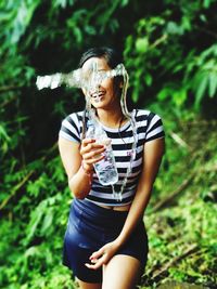 Mid section of a smiling young woman drinking water