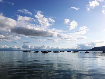 Boats in sea against cloudy sky