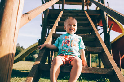 Portrait of smiling boy sitting on slide at playground