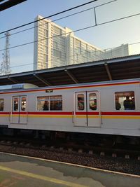 Train at railroad station in city against sky