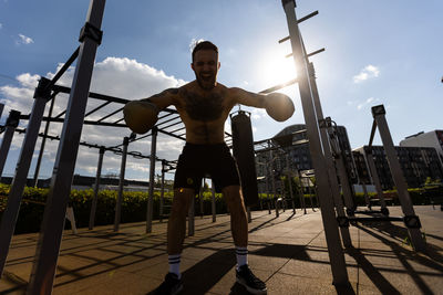 Low angle view of young man exercising at playground