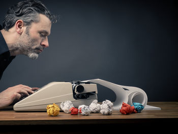 Man using typewriter against wall