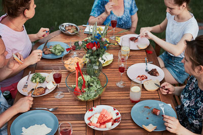 Family having a meal from grill during summer picnic outdoor dinner in a home garden