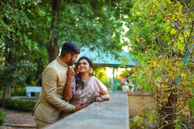 Young couple smiling against trees