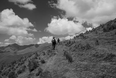 Rear view of people walking on mountain against sky