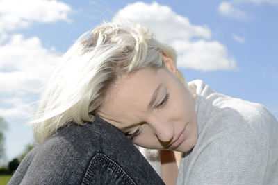 Close-up of sad woman looking down against sky