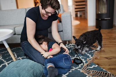 Mother playing with daughter while sitting on carpet at home