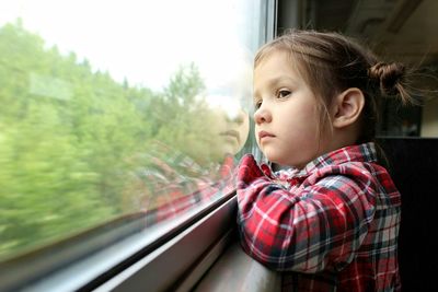 Cute girl looking through window of train