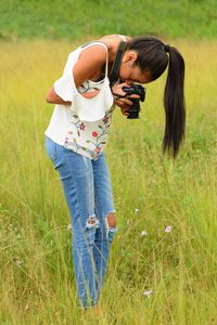 Site view of a woman standing photographing in the field.