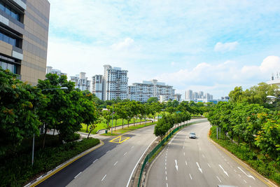 Road by buildings in city against sky