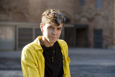 Portrait of a non binary person looking at camera while posing outdoors. person