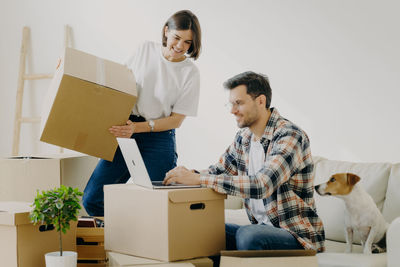 Smiling woman looking at man using laptop at home