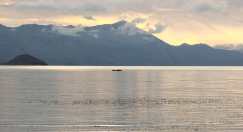 Scenic view of sea and mountains against sky during sunset