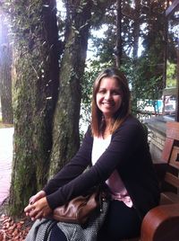 Portrait of young woman sitting on tree trunk