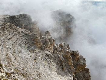 Scenic view of rock formation on land against clouds