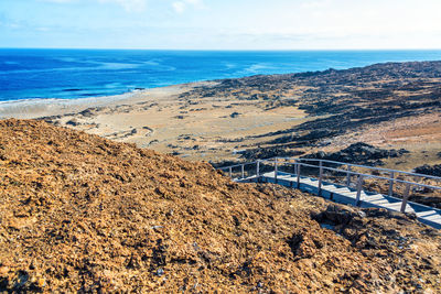 Scenic view of volcanic landscape at galapagos islands by sea against sky