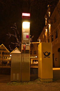 Illuminated street light by building in city at night