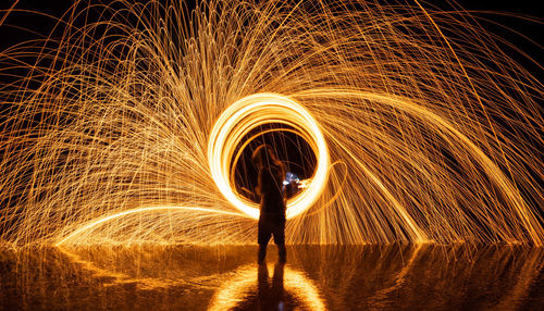 Man spinning wire wool standing in water at night