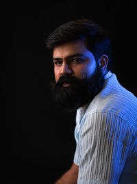 Portrait of young man against black background