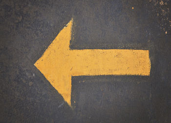 Close-up of yellow arrow symbol on road