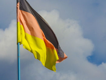 Low angle view of torn german flag against sky