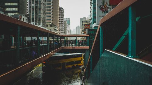 People on footbridge over bus in city during rain