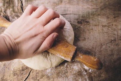 Cropped hand of woman kneading dough on wooden table