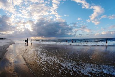 People on beach against sky during sunset