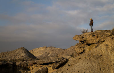 Adult man in cowboy hat standing on top of cliff in tabernas desert, almeria, spain