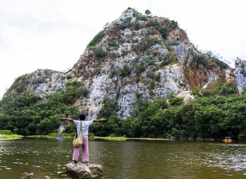 Woman standing on rock by lake against sky