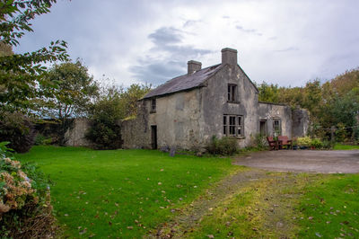 House on field by trees against sky