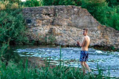Full length of shirtless man standing in lake