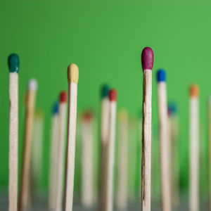 Close-up of colorful matchsticks on green background