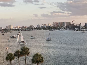 Sailboats in sea against buildings in city