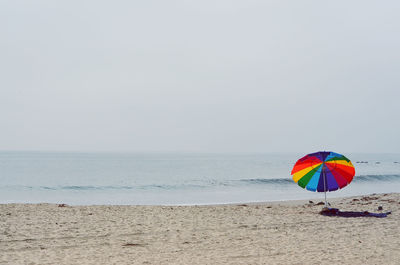 Multi colored umbrella on beach against clear sky