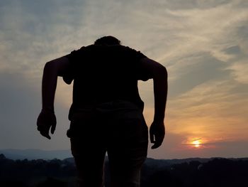 Rear view of silhouette man standing against sky during sunset