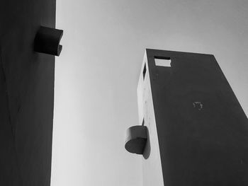 Low angle view of street light by building against sky