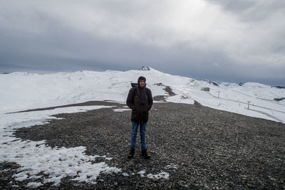 Full length of man standing on road against snowcapped mountains