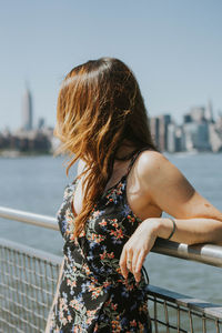 Woman standing by railing against river