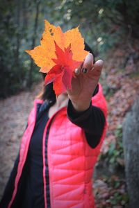 Woman holding dry autumn leaves in front of face