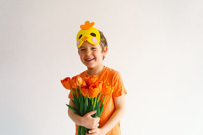 Happy boy with bouquet standing against white background