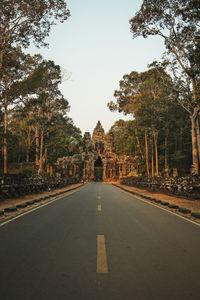 Road amidst trees against sky during sunset