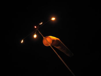 Low angle view of illuminated light bulb against black background