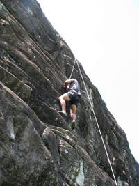 Low angle view of woman standing on cliff against mountain